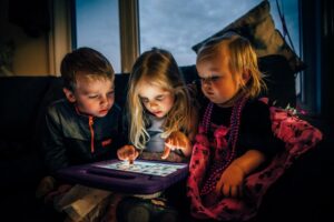 Drei Kinder spielen an einem Kindertablet