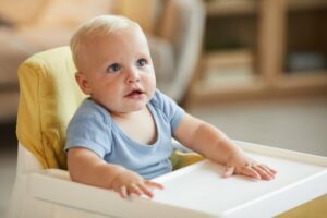 Kleinkind sitzt im Kinderhochstuhl.