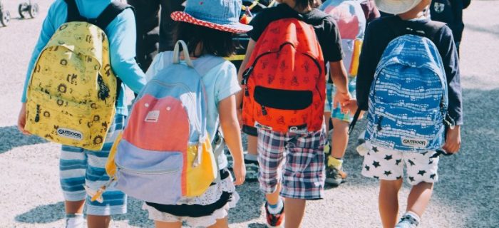 Kinder mit einem Rucksack laufen