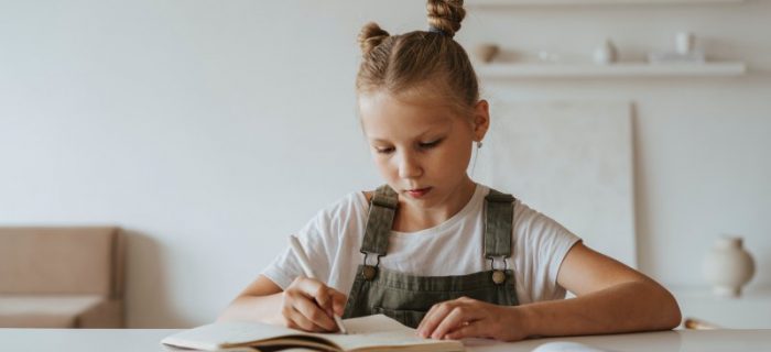 Mädchen schreibt an einem Kinderschreibtisch